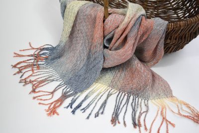 Handwoven and hand-painted scarf draped over a basket.