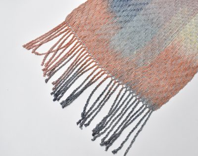 Multi-colored handwoven and hand-painted scarf using Tencel yarn. Hand twisted fringe is in view.